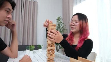 Gülen çift oturma odalarında ahşap oyunlar oynayarak eğleniyor. Sevgi kavramı, rahatlama ve evdeki eğlenceli anlarda bağlanma..