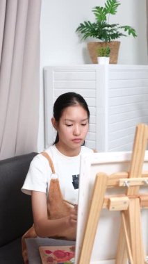 Sevimli genç kız evde resim çizerek ve boyayarak en sevdiği aktiviteyle yaratıcılığını ifade ediyor. Çocukluk hayal gücü, sanat ve oyun yoluyla öğrenme kavramı.