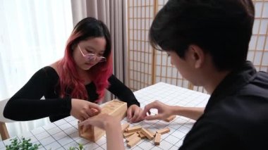 Gülen çift oturma odalarında ahşap oyunlar oynayarak eğleniyor. Sevgi kavramı, rahatlama ve evdeki eğlenceli anlarda bağlanma..