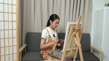 Sevimli genç kız evde resim çizerek ve boyayarak en sevdiği aktiviteyle yaratıcılığını ifade ediyor. Çocukluk hayal gücü, sanat ve oyun yoluyla öğrenme kavramı.