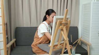 Sevimli genç kız evde resim çizerek ve boyayarak en sevdiği aktiviteyle yaratıcılığını ifade ediyor. Çocukluk hayal gücü, sanat ve oyun yoluyla öğrenme kavramı.