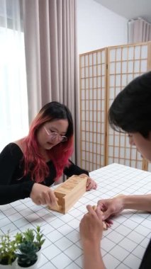 Gülen çift oturma odalarında ahşap oyunlar oynayarak eğleniyor. Sevgi kavramı, rahatlama ve evdeki eğlenceli anlarda bağlanma..