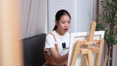 Sevimli genç kız evde resim çizerek ve boyayarak en sevdiği aktiviteyle yaratıcılığını ifade ediyor. Çocukluk hayal gücü, sanat ve oyun yoluyla öğrenme kavramı.