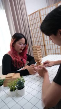 Gülen çift oturma odalarında ahşap oyunlar oynayarak eğleniyor. Sevgi kavramı, rahatlama ve evdeki eğlenceli anlarda bağlanma..