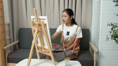 Sevimli genç kız evde resim çizerek ve boyayarak en sevdiği aktiviteyle yaratıcılığını ifade ediyor. Çocukluk hayal gücü, sanat ve oyun yoluyla öğrenme kavramı.