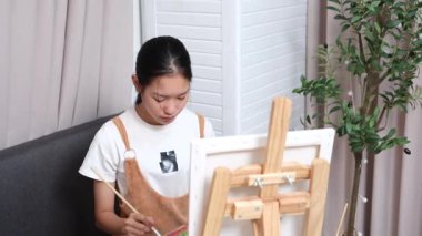 Sevimli genç kız evde resim çizerek ve boyayarak en sevdiği aktiviteyle yaratıcılığını ifade ediyor. Çocukluk hayal gücü, sanat ve oyun yoluyla öğrenme kavramı.