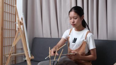 Sevimli genç kız evde resim çizerek ve boyayarak en sevdiği aktiviteyle yaratıcılığını ifade ediyor. Çocukluk hayal gücü, sanat ve oyun yoluyla öğrenme kavramı.