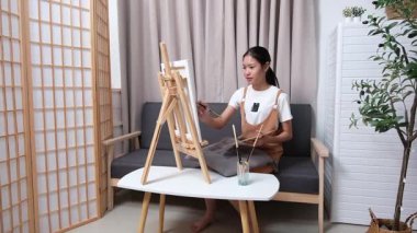 Sevimli genç kız evde resim çizerek ve boyayarak en sevdiği aktiviteyle yaratıcılığını ifade ediyor. Çocukluk hayal gücü, sanat ve oyun yoluyla öğrenme kavramı.