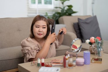 Saçını düzleştirici ile şekillendirirken günlük rutininde kendine güvenini ve güzelliğini yansıtıyor..