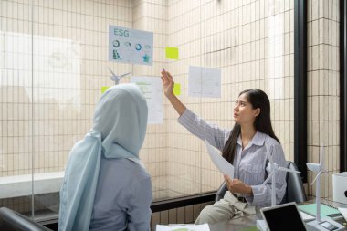 ESG Çevre, Sosyal, Yönetim girişimleri hakkında ortak bir tartışmaya giren iki profesyonel, fikir ve stratejilerini göstermek için çizelge ve modeller kullanıyor.