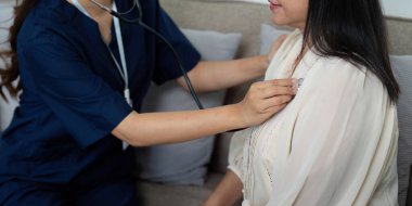 Bakıcı, yaşlı bir hastaya eşlik ederken göğüs muayenesi yapar ve evde sağlık kontrolünün önemini gösterir..