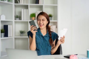 Finansal planlama başarısını kutlayan ve kayıtlarıyla ilgilenen kadın, iyi haber alınca sevinçten havalara uçuyor..