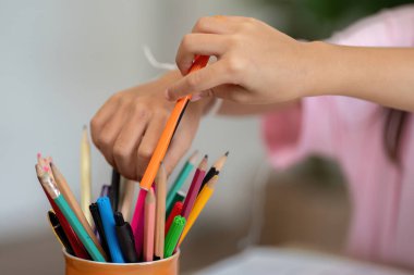 Genç bir kız renkli sanat malzemelerini dikkatlice seçer ve düzenler, canlı bir okul ortamında yaratıcı bir seansa hazırlanır..