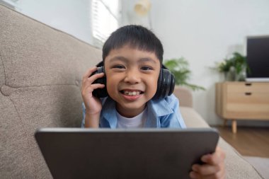 Bu resim, tabletiyle etkileşim halinde olan ve okula hazırlanma ve öğrenme sevincini vurgulayan gülümseyen bir çocuğu gösteriyor..