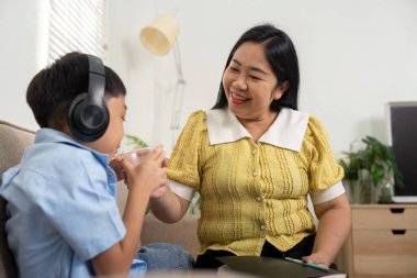 Bu iç açıcı sahnede, bir anne ve oğlu birlikte bir şeyler içiyorlar, okula dönüş dönemindeki aile anlarının neşesini sergiliyorlar..