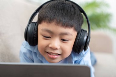 Bu resim kulaklıklı, tabletle meşgul genç bir çocuğu yakalıyor, teknolojiyle okula dönüş öğreniminin heyecanını vurguluyor..