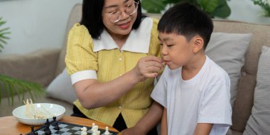 Bir anne ve oğlu eğlenceli bir satranç oyununun tadını çıkarırlar. Oturma odalarında, strateji üzerine kahkahalar atarlar ve bağ kurarlar..
