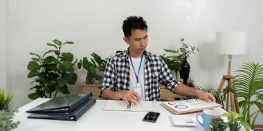 Çağdaş bir çalışma alanında çeşitli çizelge ve belgeleri analiz eden bir birey, iş analizindeki veri odaklı karar verme sürecini vurguluyor.