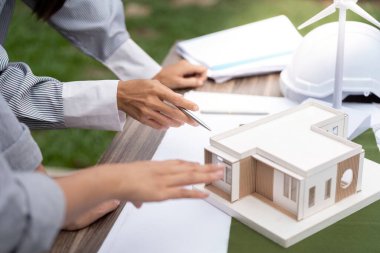 Mimarlar, sürdürülebilir bir binanın eko-dost tasarım ve yenilikçi inşaat yöntemlerini vurgulayan ayrıntılı modelini tartışıyor.