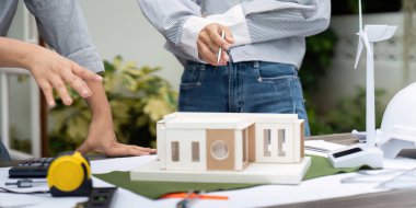 Mimarlar sürdürülebilir bir binanın detaylı bir modeli üzerinde işbirliği yaparlar, rüzgar türbinleri ve çevre dostu malzemeler gibi yenilikçi tasarım unsurları sergilerler..