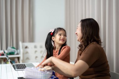 Bir anne ve kızı, birlikte öğrenmenin mutluluğunu vurgulayan okul malzemelerini hazırlarken neşeli bir anı paylaşıyorlar..