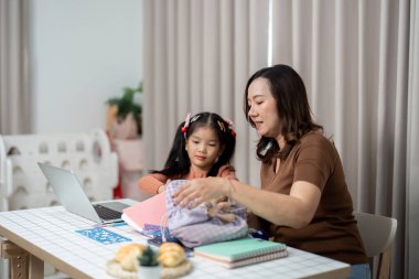 Bir anne ve kızı okul malzemelerini organize ediyor, önümüzdeki okul yılına hazırlanıyor ve sorumluluk duygusunu arttırıyorlar..