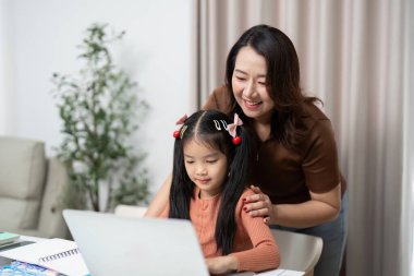 Anne ve kız, okula dönüş hazırlıklarının bir parçası olarak, dijital okuryazarlığı teşvik ederek, bir dizüstü bilgisayardan öğrenmeyi keşfediyorlar..