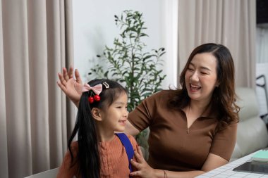 Bir anne, kızına sırt çantasını takması için yardım eder, yaklaşan okul yılı için heyecan yaratır ve hazırlığı teşvik eder..