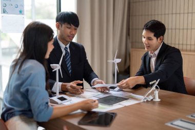 Sürdürülebilir bir ESG toplantısında bir grup profesyonel, takım çalışması ve işbirliğine odaklı yenilenebilir enerji çözümlerinin grafiklerini ve verilerini analiz ediyor.