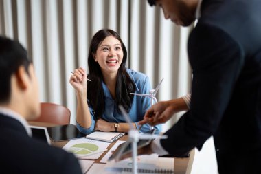 Sürdürülebilir bir ESG beyin fırtınası oturumunda gülümseyen bir profesyonel, aktif olarak katılmakta ve yenilenebilir enerji tartışmaları ve veri analizleriyle meşgul.