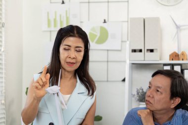 ESG odaklı bir toplantıda sürdürülebilirlik stratejileri sunan bir lider, iş arkadaşlarını daha yeşil bir gelecek için veri görselleri ve çevre dostu kavramlarla meşgul ediyor.