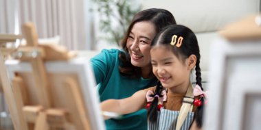 Bir anne ve kızı resim yaparken kahkahalarını paylaşıyor, yaratıcılıklarını birlikte ifade ettikleri neşeli bir atmosfer yaratıyorlar..