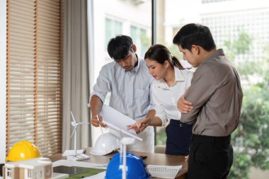 Bir ekip, sürdürülebilir uygulamaları ve çalışma alanındaki yenilikçi tasarımları vurgulayarak, mimari proje planlaması üzerinde işbirliği yapmaktadır..