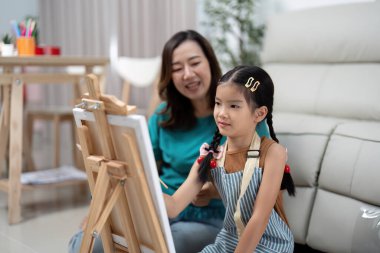 Bir anne ve kızı keyifli bir resim seansının keyfini çıkarırlar, resim projesi üzerinde çalışırken gülüşlerini ve yaratıcılıklarını paylaşırlar..