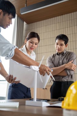 Çevresel etki raporlarını ve yenilikçi çözümleri parlak, modern bir ofiste tartışan sürdürülebilirlik mühendislerinden oluşan bir ekip.