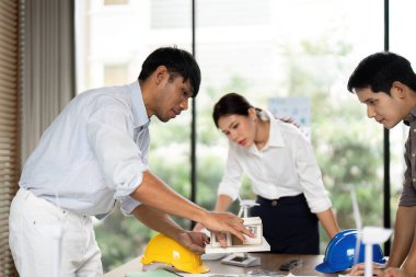 Takım üyeleri proje tartışmalarında yer alarak, modern bir ofiste gelecekteki mimari tasarımlar için sürdürülebilir çözümler araştırıyorlar..
