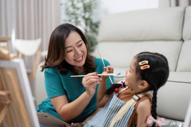 Bir annenin resim yaparken kızıyla yaratıcılığını paylaştığı, hem gülümseyen hem de sanatla bağ kurduğu bir an..