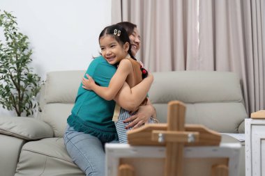 Bir anne ve kızı sıcak bir kucaklaşmayı paylaşır, evlerinde sevgi ve mutluluk gösterirler..