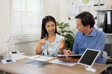 Bir sürdürülebilirlik toplantısında iki profesyonel, ESG sunumları ve stratejileri, takım çalışması ve çevre dostu çözümlere adanmışlığı tartışıyor.