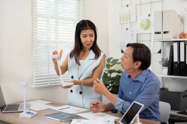 Sürdürülebilirlik çabalarında işbirliği yapan, ESG grafiklerini analiz eden ve ekolojik performansı artırma stratejilerini tartışan iki profesyonel.