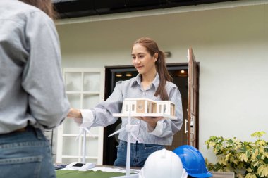 Açık hava ortamında bir müşteriye çevre dostu yapı modelleri ve yenilenebilir kaynaklar sunan sürdürülebilirlik mühendisi, işbirliği ve yeniliği vurguladı.