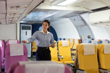 Bir havayolu çalışanı yolcu oturma düzenini kontrol ederek yolcuların rahat bir şekilde seyahat etmesini sağlar..