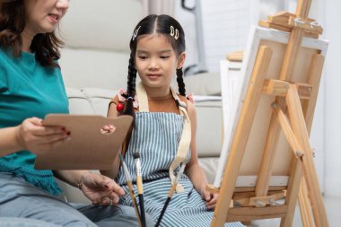 Bir anne kızına yaratıcı bir resim seansında rehberlik eder. Parlak oturma odasında tavsiyelerini ve cesaretini paylaşır..