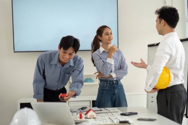 Meslektaşlar proje detayları hakkında canlı tartışmalara girerken, inşaat modellerini analiz ediyorlar, takım çalışmasını ve yenilikleri teşvik ediyorlar.