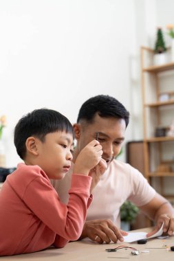 Bir baba ve çocuk, evde çeşitli bilim malzemelerini birleştirmeye odaklanmış, keşif ve öğrenme sürecinin tadını çıkarıyorlar..