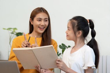 Bir anne ve kız, evde çalışırken, öğrenme ve etkileşim yoluyla okula dönüş heyecanını kucaklarken, keyifli bir anı paylaşıyor..