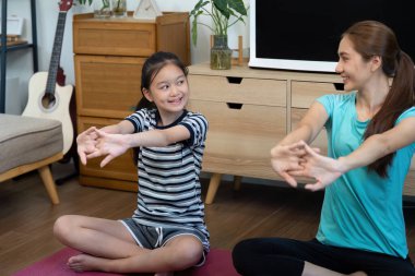 Bir anne ve kızın yoga pozisyonlarını esnetme, evdeki refahı ve farkındalığı arttırma gibi eğitici bir an..