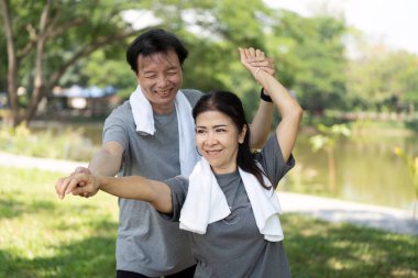 Mutlu bir son sınıf çifti dışarıda keyifli yoga egzersizleri yapıyor. Spor salonu, sağlık ve dışarıdaki bağlantıyı birleştiriyor..