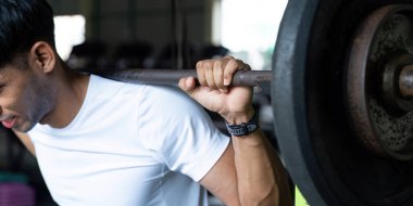 Zindelik ortamında ağırlık kaldırırken odaklanmış bir birey güç ve kararlılık gösterir.