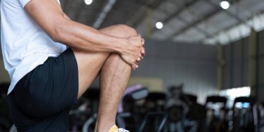 Spor salonunda egzersiz yaparken dizini tutan genç bir adam, spor yaparken sağlık durumunu ve sakatlığı önlediğini vurguladı..